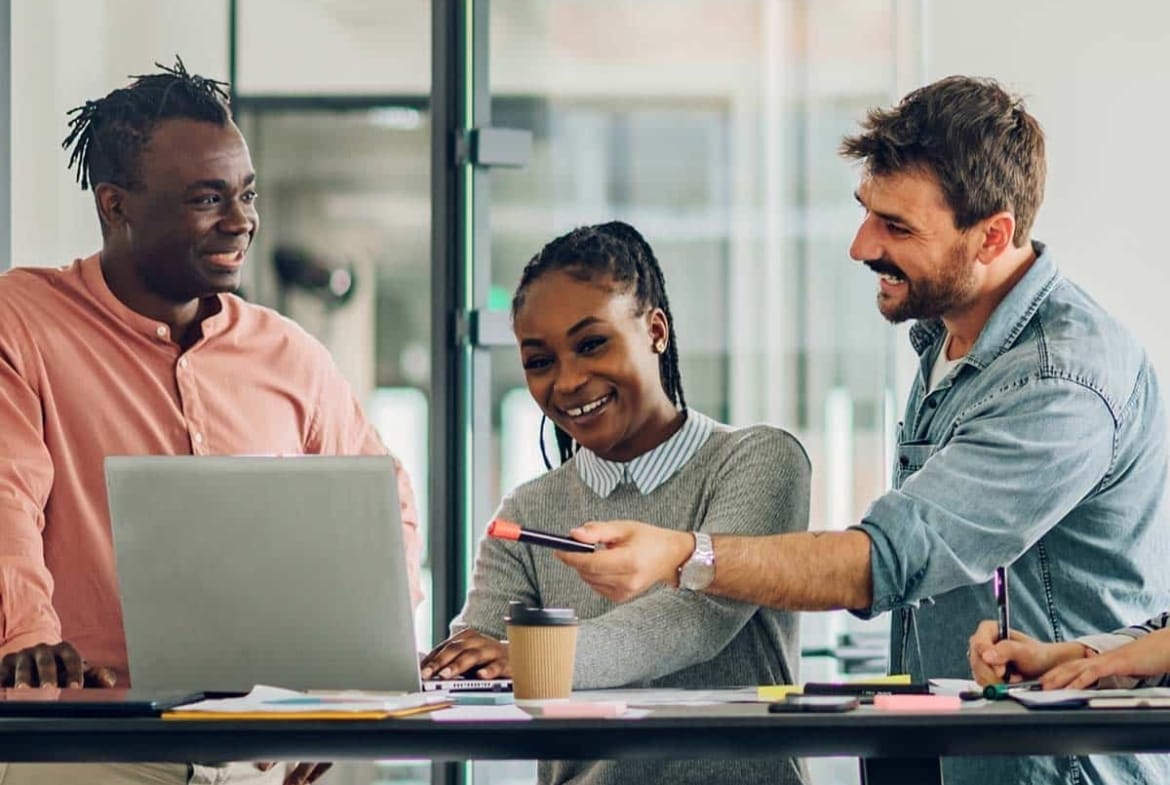 A group of people sitting around a table looking at a laptop, discussing new homes in GTA.