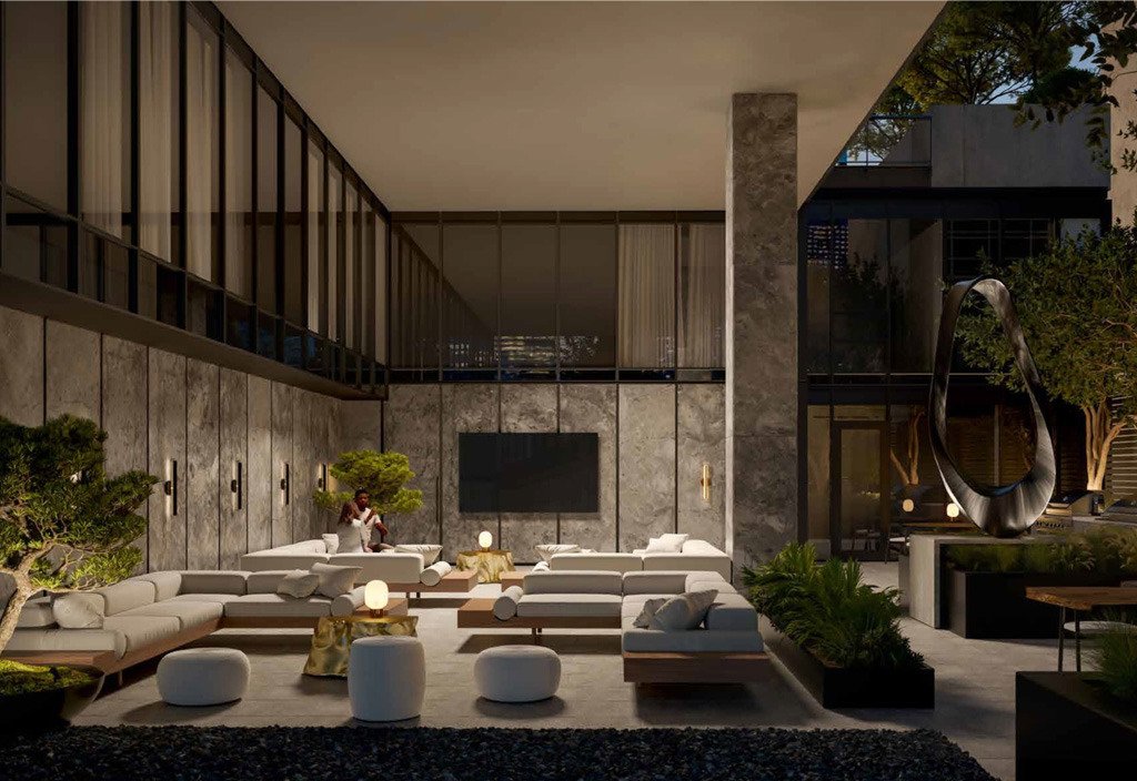 An elegant living room in a new home showcases plush seating, a large TV, and ambient lighting. The space accentuates greenery, marble walls, and floor-to-ceiling windows. With someone seated on the couch, this stylish interior offers a cozy and lived-in ambiance.