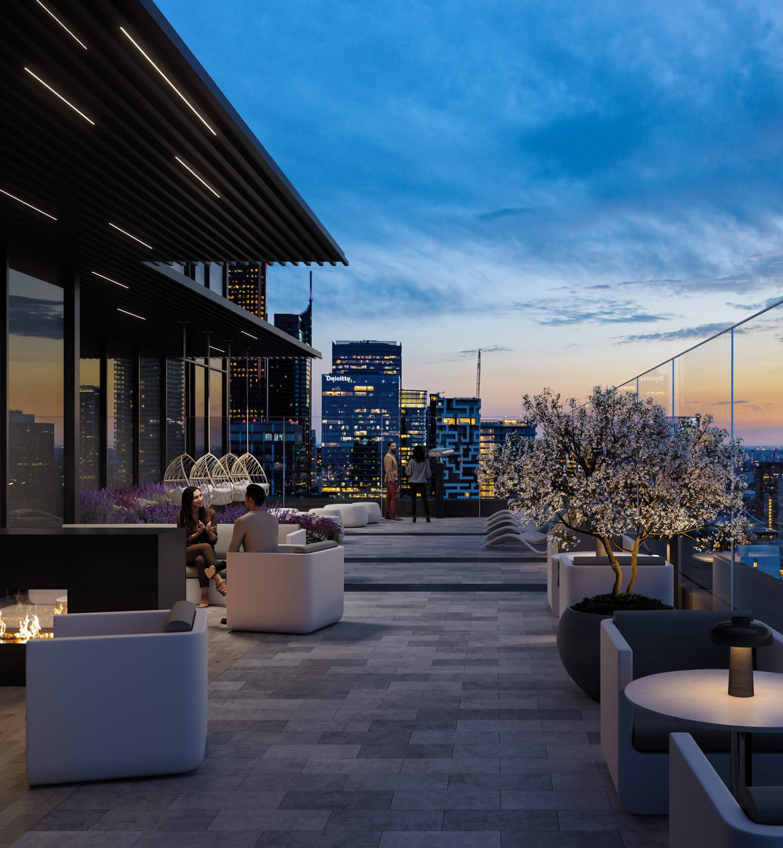 A modern rooftop patio at dusk, featuring cozy seating areas with a fire pit and potted plants, including a blossoming tree. City skyscrapers are visible in the background against a colorful sunset sky. A few people are seated, enjoying the ambiance of New Homes in GTA as they view Pre Construction Homes nearby.
