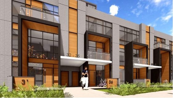 A modern row of townhouses with large windows and orange wooden accents awaits buyers looking for new homes in GTA. Each unit has a small balcony and framed entrance, identified by black numbers "32," "34," and "36." A person is walking on the sidewalk towards the door of number "36.