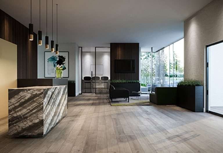 Modern minimalist interior of a lobby area with wooden flooring, a marble reception desk, hanging pendant lights, black and green seating, and large windows allowing natural light. A framed artwork is on the wall, and greenery is visible outside the windows. Perfect for those seeking new homes in GTA.