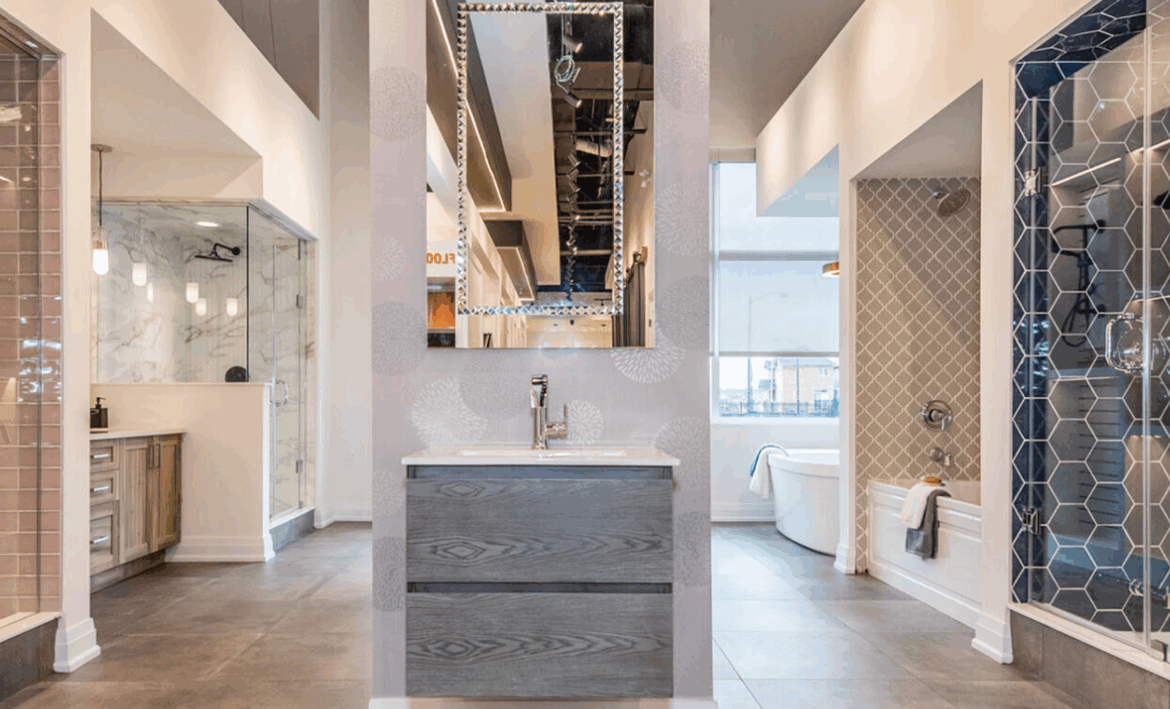 A stylish showroom display featuring modern bathroom designs, perfect for pre-construction homes. The centered vanity with a rectangular mirror is flanked by diverse shower and bathtub setups showcasing contemporary tiles, fixtures, and finishes. The overall look is sleek and sophisticated.