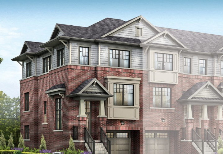 A three-story townhouse with a combination of red brick and gray siding. The building features multiple peaked roofs, large black-framed windows, and small front porches with black railings. Perfect for those seeking new homes in GTA, the landscaping includes green shrubs and trees.