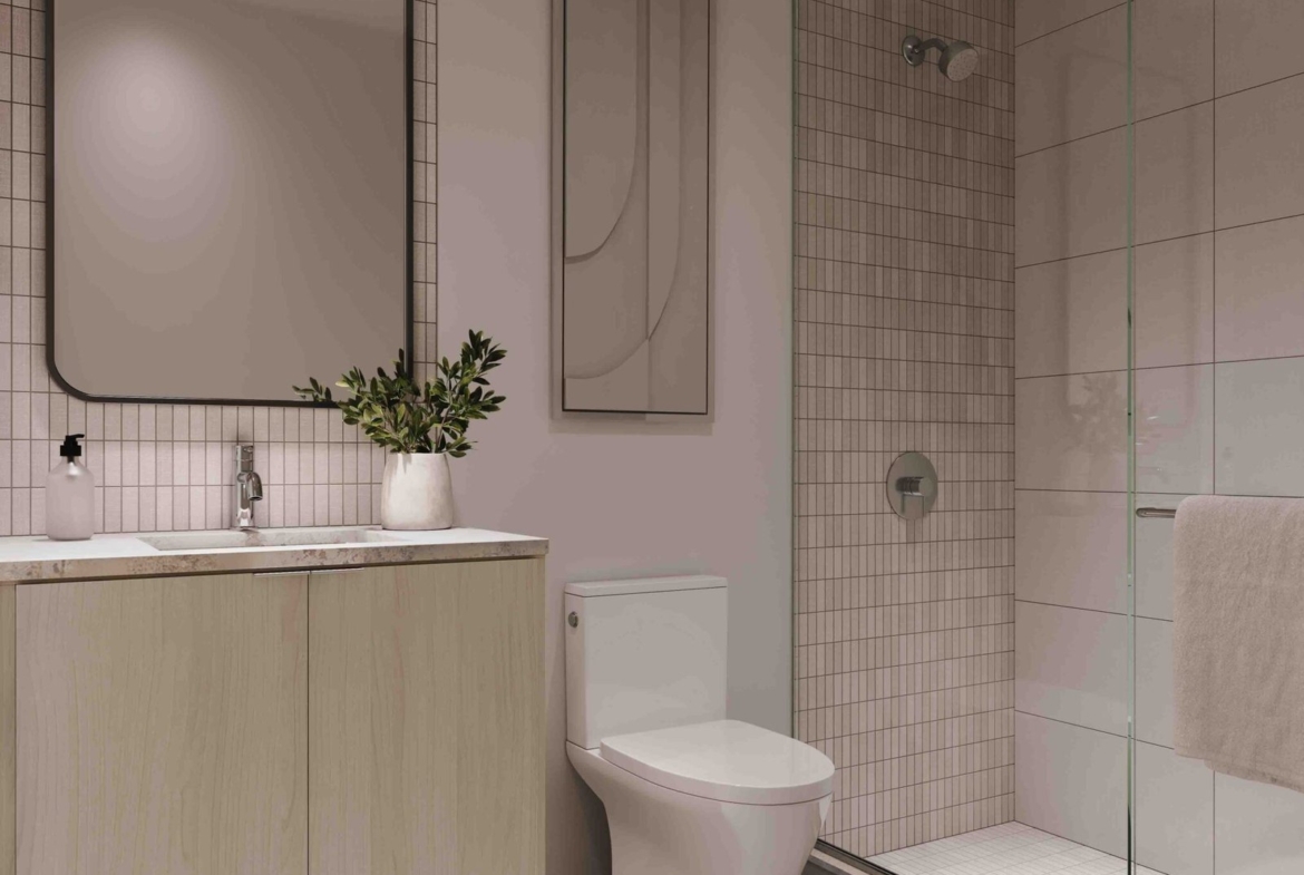 Modern bathroom in Gagan Bector with soft pink walls, a wooden vanity with a rectangular mirror, a glass-enclosed shower, beige tiles, and subtle lighting.