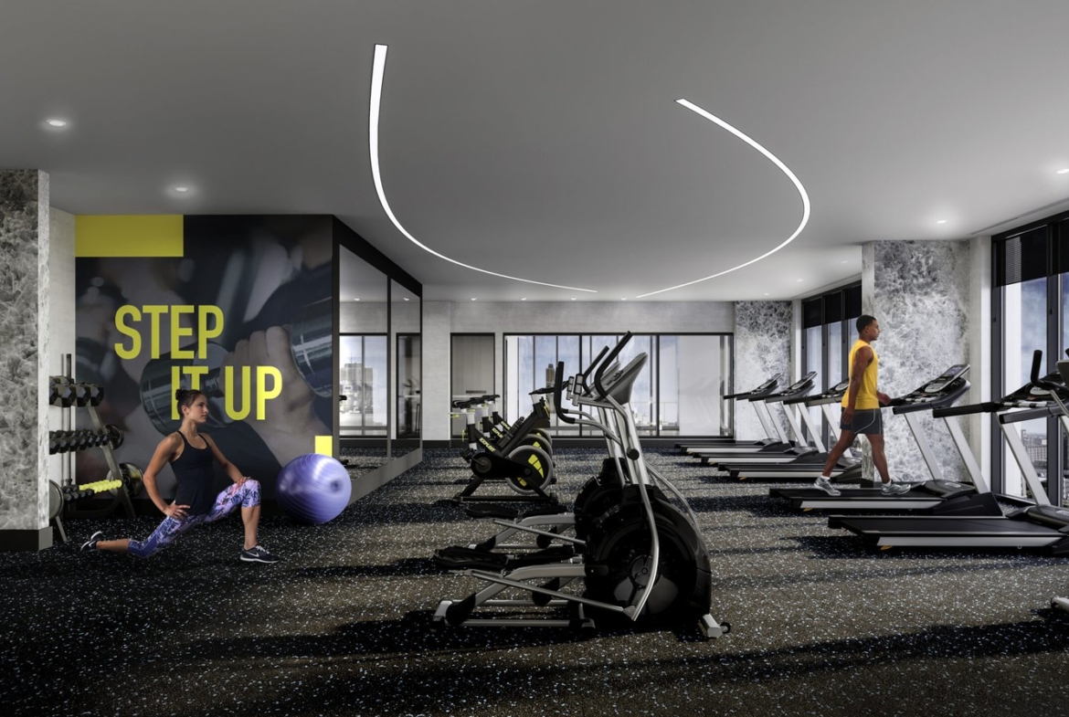 A modern gym with large windows and various exercise equipment. A person on the left is stretching using a stability ball, while another on the right is walking on a treadmill. A wall in the background features the text "STEP IT UP" in large, bold letters—a perfect amenity for those investing in new homes in GTA.