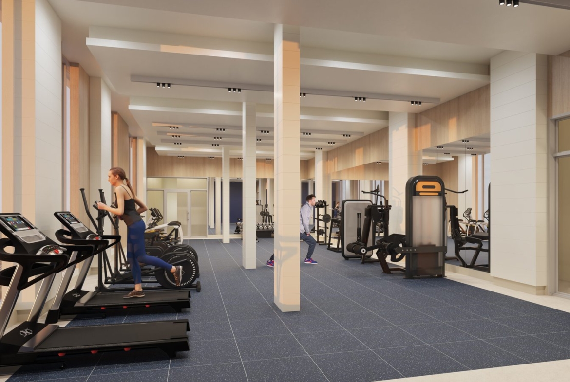 A modern gym in one of the new homes in GTA, featuring large windows, a blue-tiled floor, and beige walls. Three treadmills are in the foreground, one occupied by a woman running. Further back, a man is using weights. Various other workout machines are visible throughout the space.