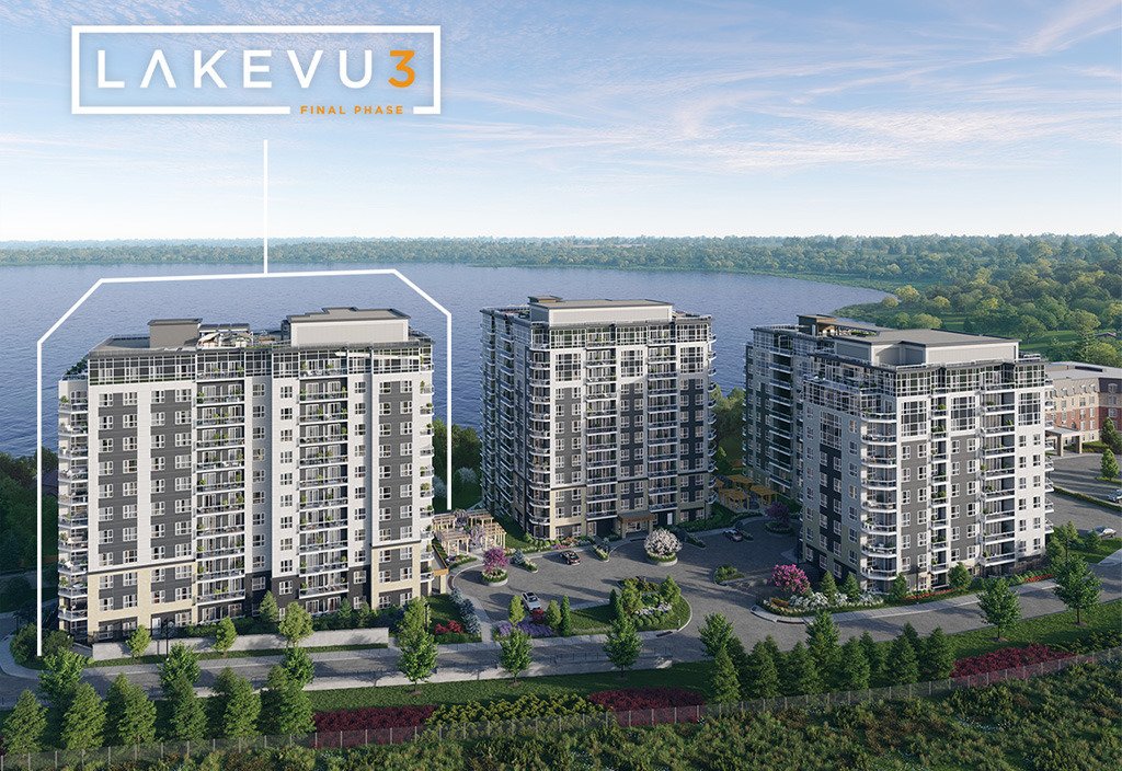 Aerial view of three modern high-rise buildings labeled "Lakevu3 Final Phase" near a lake. These new condos in Brampton are surrounded by lush greenery and a road, with the lake and trees creating a tranquil backdrop under a partly cloudy sky.
