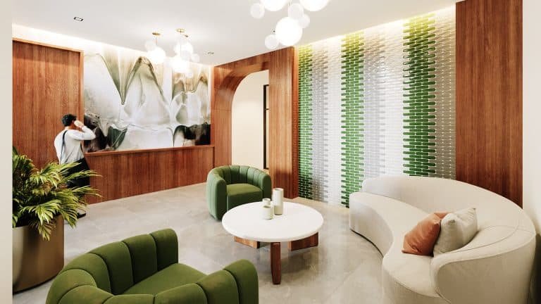 The lobby at Motto Condos features green armchairs, a white circular table, and a curved white sofa with an orange cushion. The walls are adorned with wood paneling, a green and white tiled design, and a large floral mural. Ceiling lights illuminate the space, and a plant is in the foreground.
