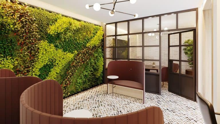 A modern lounge area at Motto Condos features curved, brown seating booths, a small table, and a large vertical garden on one wall. Glass partition walls with black frames divide the space, while the floor is patterned with small tiles in various shades of brown and white. Experience the best in urban living here.