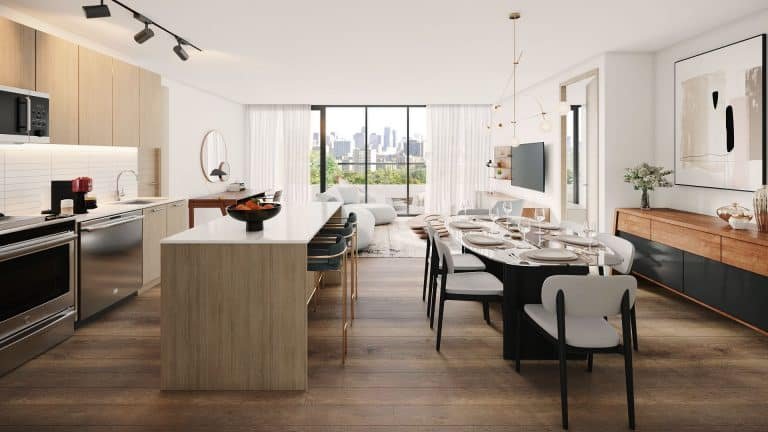 A modern, open-concept kitchen and dining area at Motto Condos boasts light wood cabinetry, an island with bar stools, a dining table set for six, and a living room in the background. Large windows allow natural light to illuminate the space while offering a stunning view of the city skyline.