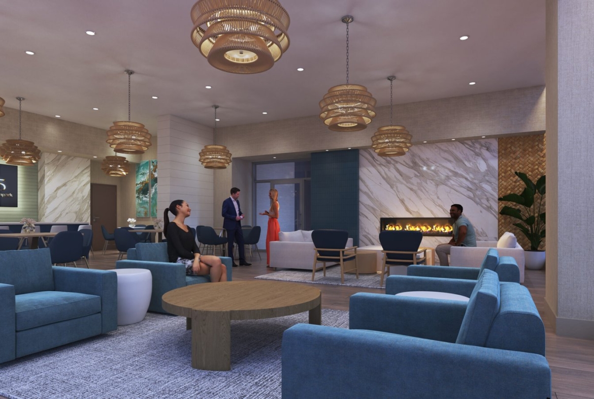A modern lounge area with people socializing in new homes. The room has contemporary decor, featuring blue armchairs, round wooden tables, and pendant lights. A fireplace with a glowing orange flame is set into a marble wall. Art pieces adorn the walls, complementing the stylish setting.