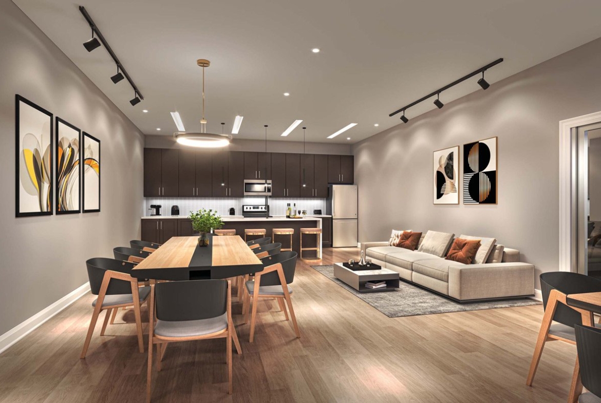 Modern open-plan living space featuring a kitchen with dark cabinetry, a dining area with a large wooden table, and a lounge with beige sofa, all under warm ambient lighting in New Condos