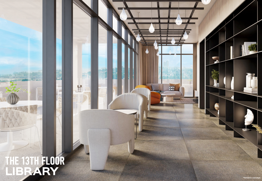 A modern library on the 13th floor of new condos in GTA features floor-to-ceiling windows with a city view. It has minimalist furniture, including white chairs and an orange sofa. Black shelving units display books and decorative items. Pendant lights hang from the ceiling.