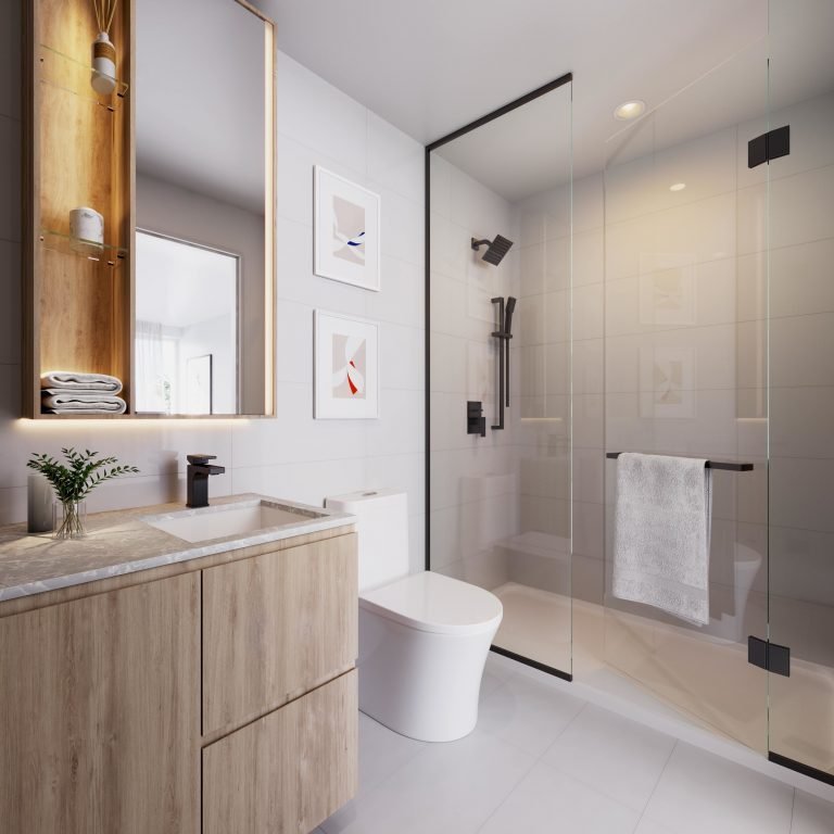 A modern bathroom at Six99 Condos features a glass-enclosed shower, wooden vanity with a marble countertop, and a white toilet. The vanity has a large mirror and shelves with rolled towels. Two framed abstract artworks hang on the white tiled wall. A plant adds a touch of greenery.