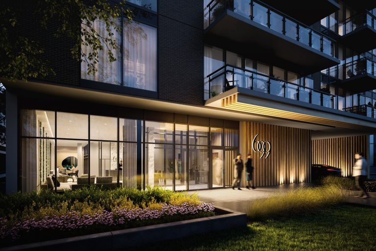 The image shows the modern entrance of Six99 Condos at dusk. The exterior features large glass windows and wooden paneling. Two people are walking towards the door, and landscaped greenery is in the foreground.