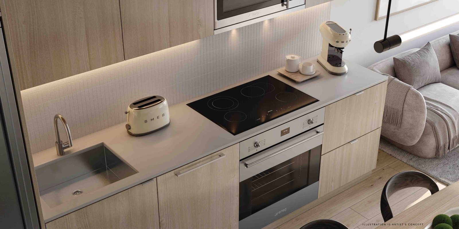Modern kitchen interior featuring light wood cabinets, a sleek induction stove, built-in oven, and small appliances in a pre-construction home. A cozy seating area with a gray sofa is visible adjacent Modern kitchen interior featuring light wood cabinets, a sleek induction stove, built-in oven, and small appliances in a pre-construction home. A cozy seating area with a gray sofa is visible adjacent