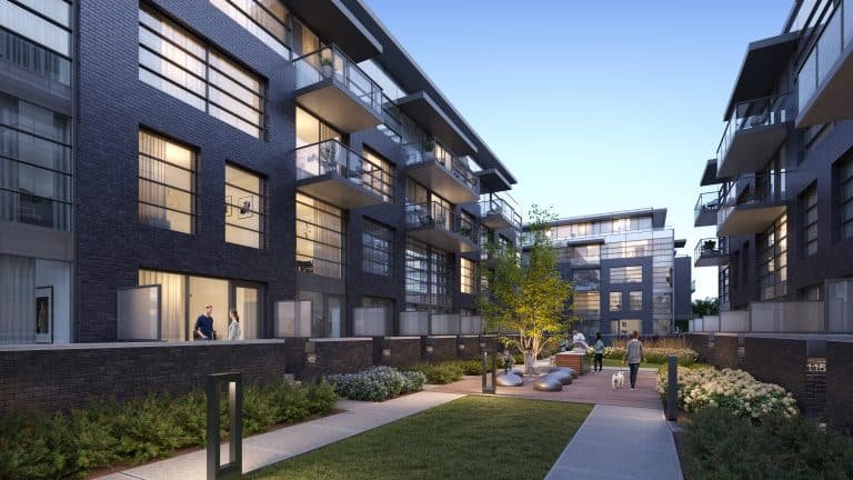 Evening image of Landing Condos at Whitby Harbour featuring dark brick exteriors and large windows. A few residents are seen on balconies and walkways. There is a small courtyard with trees, benches, and pathways, and some people are walking their dogs.