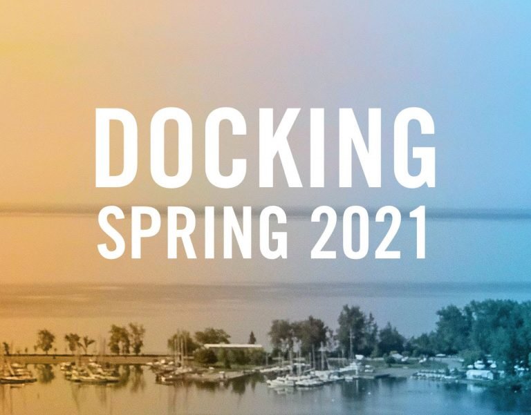 An image featuring the text 'DOCKING SPRING 2021' overlaid on a gradient background transitioning from orange to blue. Below the text, there is a serene marina scene with boats docked and trees along the shoreline at Whitby Harbour, framed by the beautiful Landing Condos.