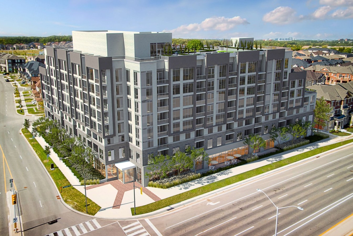 A modern, multi-story apartment building with large windows stands surrounded by trees on a street corner. The area offers a suburban feel with houses in the background and multiple lanes on the roadway. Explore new homes in this vibrant setting, perfect for those seeking contemporary living spaces.