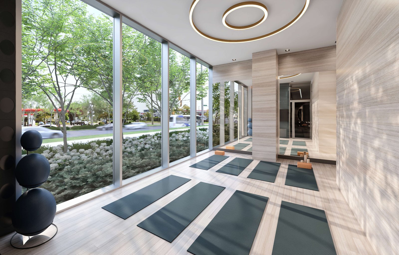 A modern, serene yoga studio with floor-to-ceiling windows showcases a landscaped outdoor view. Green yoga mats are neatly arranged on the wooden floor, while circular ceiling lights enhance the elegance of the minimalist design—mirroring the tranquility found in new homes in Toronto.