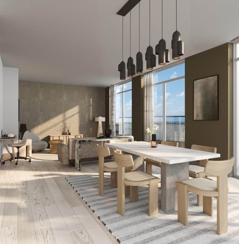 A modern, sunlit dining room in new homes in GTA featuring a light wood table surrounded by matching chairs, and pendant lights overhead, adjacent to a cozy living area with large windows.