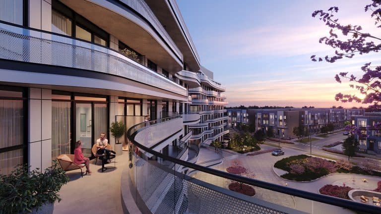 Two people sitting on a balcony enjoying a conversation, with a panoramic view of new condos at dusk, trees subtly lit and streets gently winding through the complex.