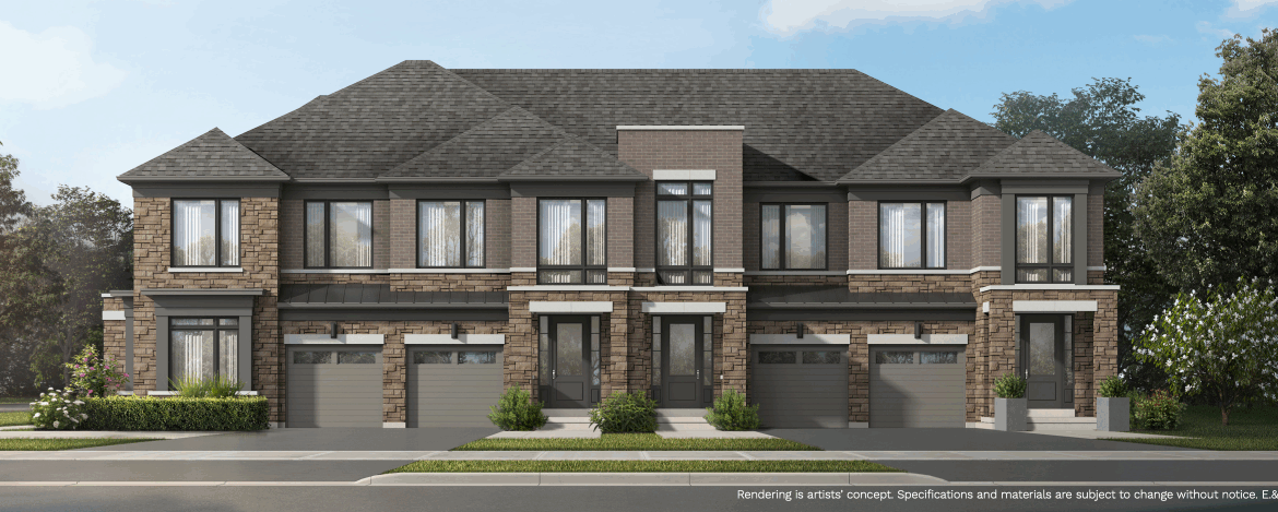 A modern townhouse complex with brick and stone exterior features two stories and attached garages. The building is surrounded by neatly trimmed bushes and trees under a clear blue sky, offering an appealing option for those seeking new condos in Brampton.