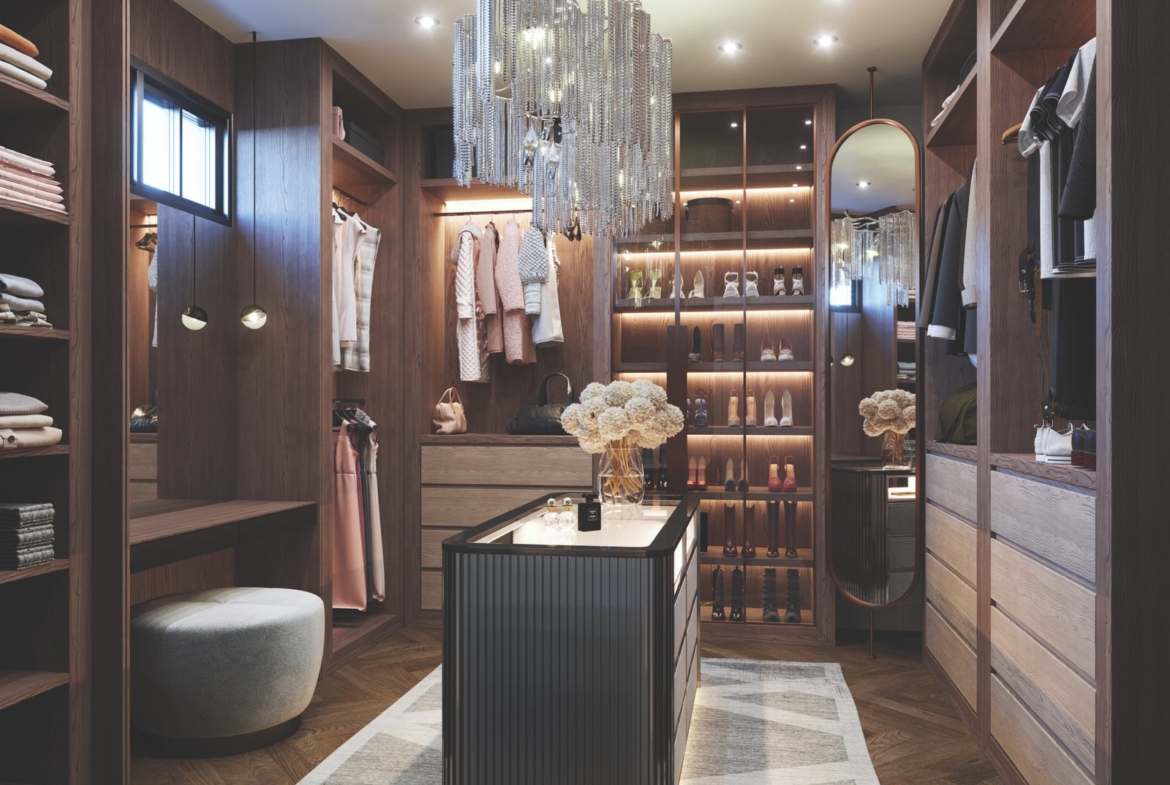 A luxurious walk-in closet with wooden shelves filled with clothes and shoes, perfect for new homes. A central island is adorned with decorative flowers under a glamorous crystal chandelier. Soft lighting creates a warm ambiance, highlighting elegant décor and design.