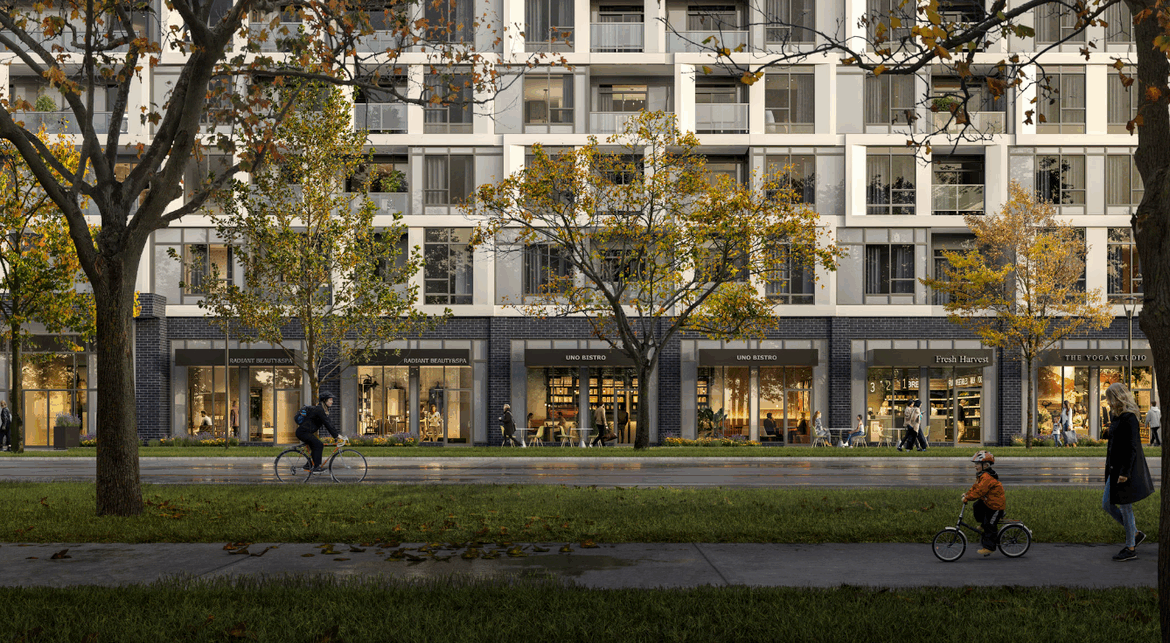 Discover new condos in the GTA within this modern apartment building, boasting retail shops on the ground floor. People stroll and ride bicycles along a tree-lined sidewalk, with autumn leaves scattered across the grass.