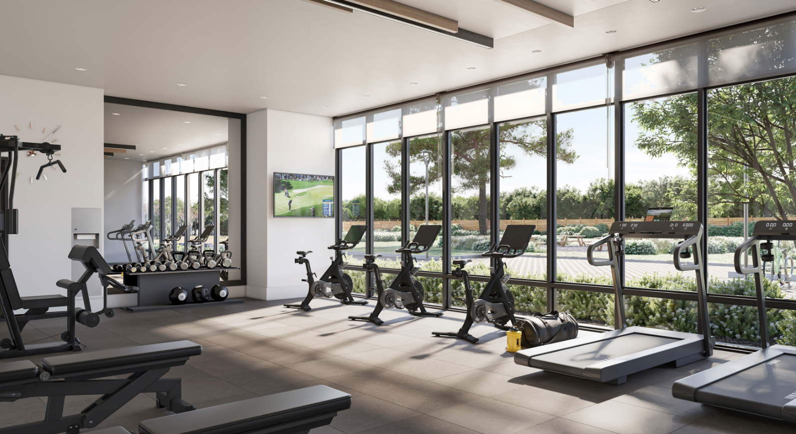 A modern gym with large windows offers a leafy view and includes exercise bikes, treadmills, and weightlifting equipment. Perfect for residents of new homes in Toronto, a TV displays sports while natural light fills the room, highlighting a clean and organized space. A modern gym with large windows offers a leafy view and includes exercise bikes, treadmills, and weightlifting equipment. Perfect for residents of new homes in Toronto, a TV displays sports while natural light fills the room, highlighting a clean and organized space.