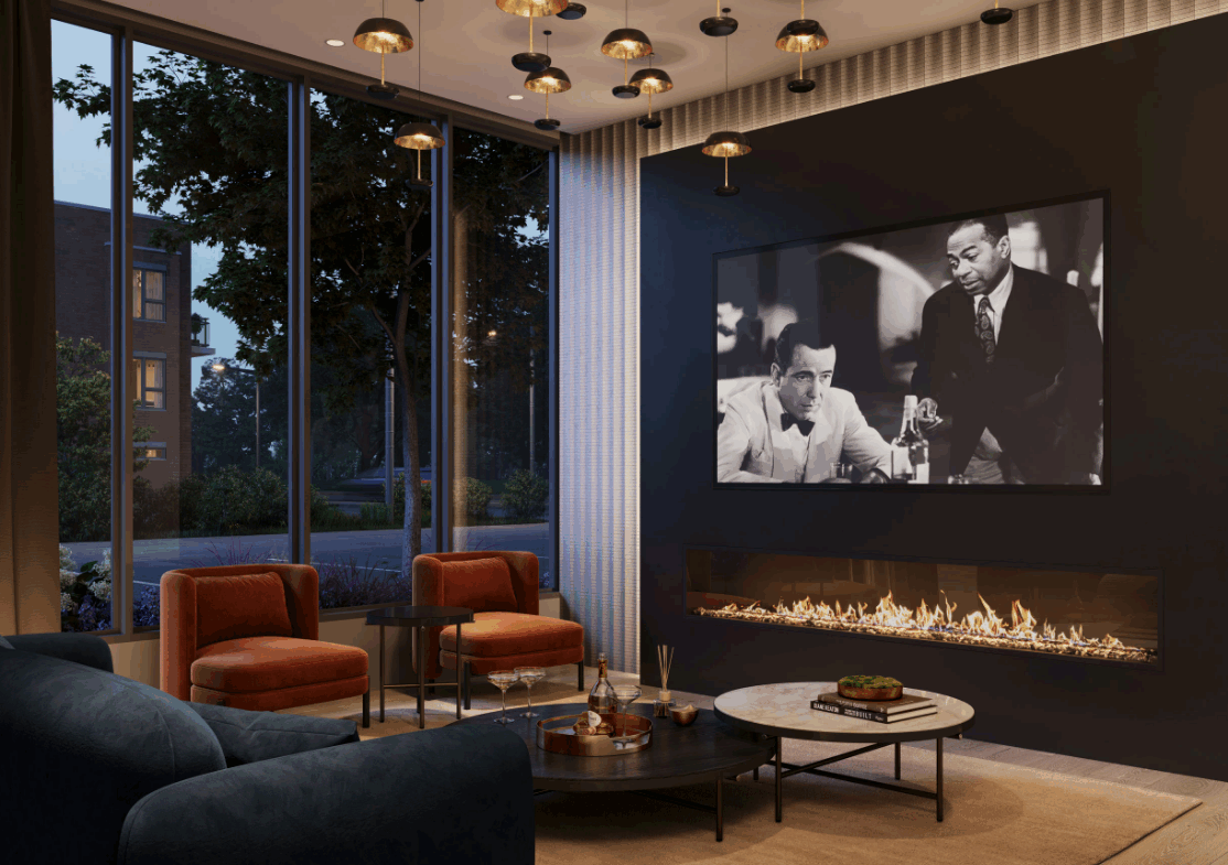A modern living room in new homes features a sleek fireplace, a large black-and-white movie still on the wall, two orange armchairs, a dark sofa, and a round coffee table. Floor-to-ceiling windows reveal an evening cityscape, while hanging lights add warmth.