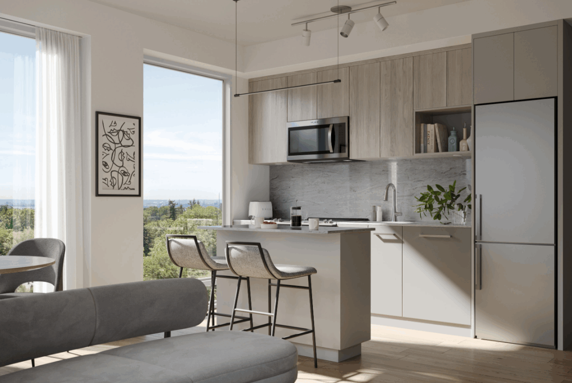This modern kitchen interior features gray cabinets and a sleek island with barstools. A large window offers a view of greenery, while wall art and a potted plant add decorative touches. A micro-oven and stainless steel fridge complete the look, ideal for new homes with style-focused design.