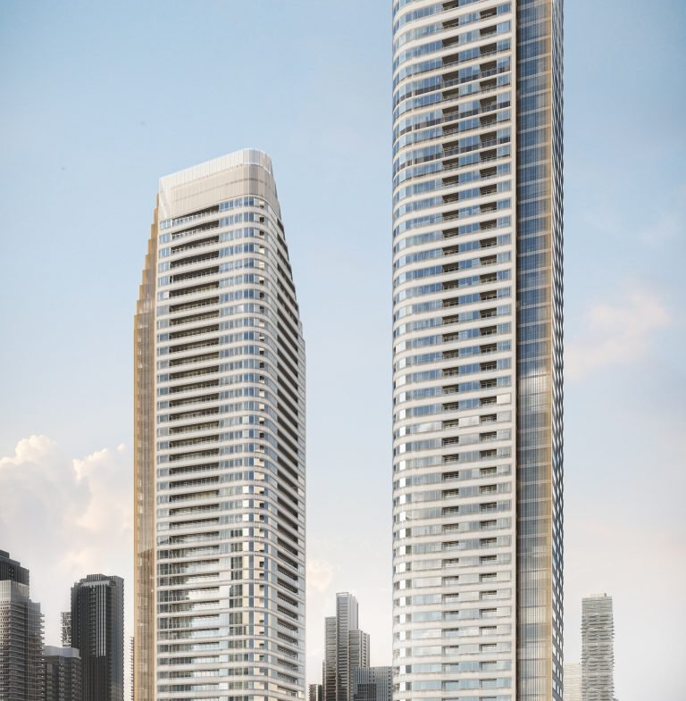 Two modern high-rise buildings, Park Place VMC condos, with sleek, curved designs stand side by side against a clear sky. Surrounded by other skyscrapers and greenery at their bases, the facade reflects light, highlighting the vibrant urban setting.