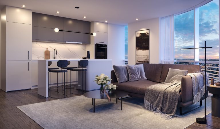 A modern living room at Park Place VMC boasts a sleek kitchen. The space features a brown sofa with gray pillows, a coffee table with flowers, two bar stools at the island, and large windows showcasing a sunset view. The decor is minimalist and elegant.