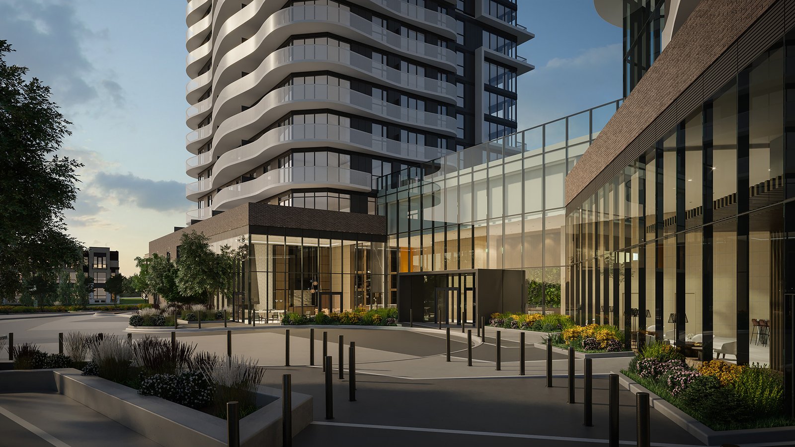 The modern urban development showcases a curved high-rise with glass and brick exteriors. In the foreground, landscaped gardens and a sleek entryway accentuate its allure against a clear sky, embodying contemporary architecture. Discover new condos in Brampton for an elevated lifestyle.