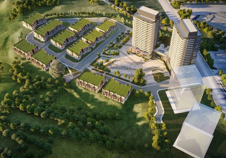 Aerial view of a modern residential complex, Ravine Towns, featuring two tall buildings and multiple low-rise structures with green roofs, surrounded by trees and greenery. Pathways and roads connect the development, situated near an open landscape reminiscent of a serene SXSW retreat.