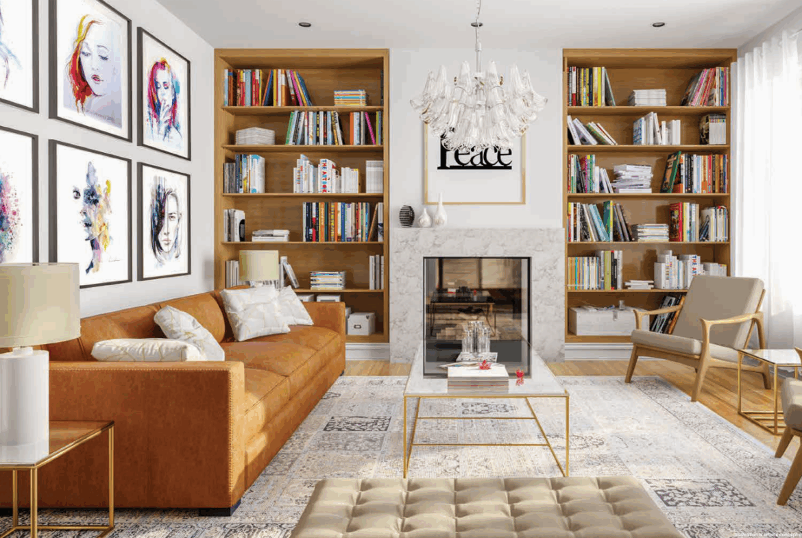 A stylish living room in one of the new homes features a brown leather sofa, two beige chairs, a glass coffee table, and a tufted ottoman. Bookshelves flank the fireplace, and framed artwork decorates the white walls. A chandelier hangs from the ceiling as large windows illuminate the space.
