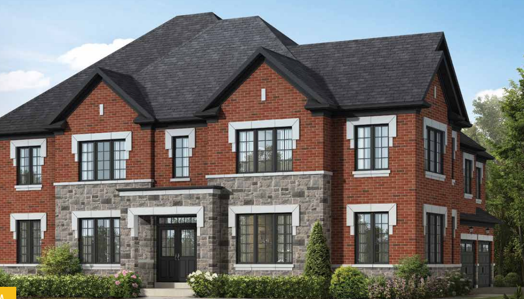 A two-story red brick house with gray stone accents and multiple windows, featuring a dark gray roof. The front yard is beautifully landscaped with small shrubs and greenery under a clear blue sky, reminiscent of the charm often found in new homes.