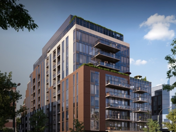 A modern multi-story building with large glass windows and balconies is surrounded by trees under a clear blue sky, creating a contemporary urban setting. Perfect for those interested in new condos in the GTA, this architecture promises stylish living amidst nature.