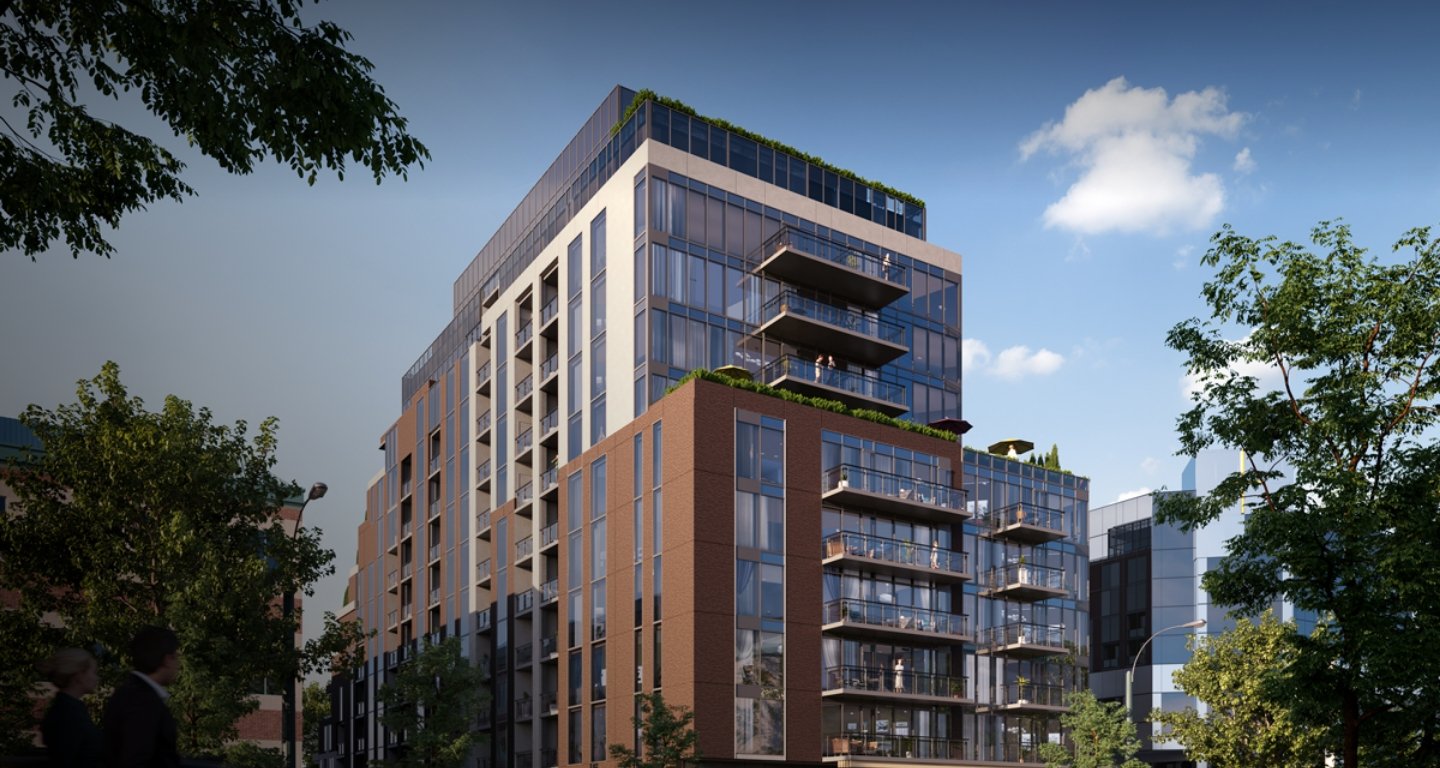 A modern multi-story building with large glass windows and balconies is surrounded by trees under a clear blue sky, creating a contemporary urban setting. Perfect for those interested in new condos in the GTA, this architecture promises stylish living amidst nature.