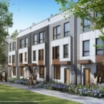 Joy Station Towns is a modern townhouse complex with three-story buildings featuring large windows and balconies. People stroll along the sidewalk bordered by trees and greenery on a sunny day.