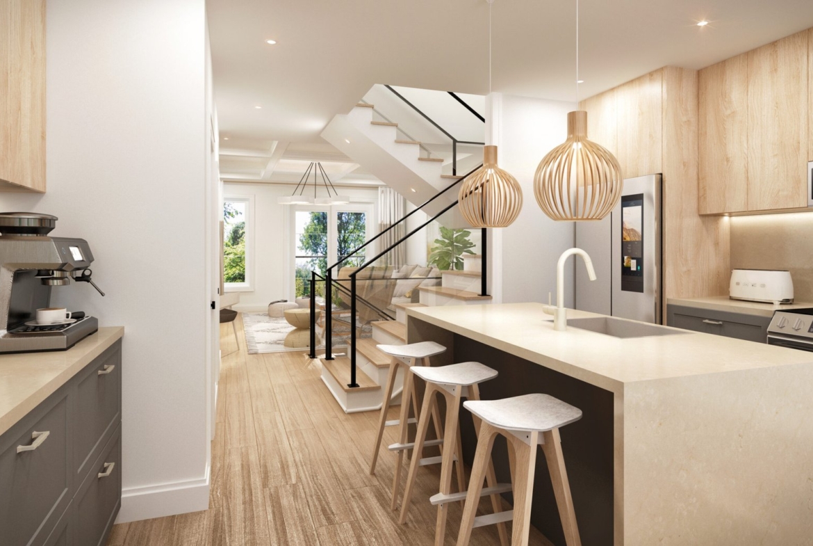 Discover a modern kitchen in new homes in Toronto, featuring light wood accents and a large island with three stools. Stylish pendant lights hang above. A staircase leads to a bright living area with cozy seating. Brown cabinets and a coffee machine are on the left, creating warmth and convenience.