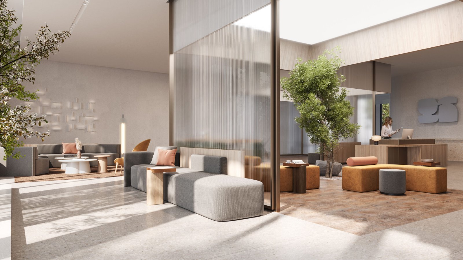 In this sophisticated condominium lobby, sleek gray and brown furniture, including sofas and ottomans, complement the space. A tree and plants add greenery near a wooden reception desk where a person stands. Soft natural light filters through large windows, enhancing the welcoming atmosphere.