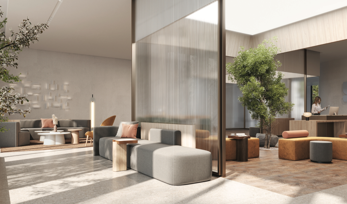 A modern, airy living space within Above Condos features gray and orange seating, large windows, and a partial glass partition. Green plants surround a person working at a desk, with soft, natural lighting enhancing the minimalist decor—ideal for luxury condominium living.