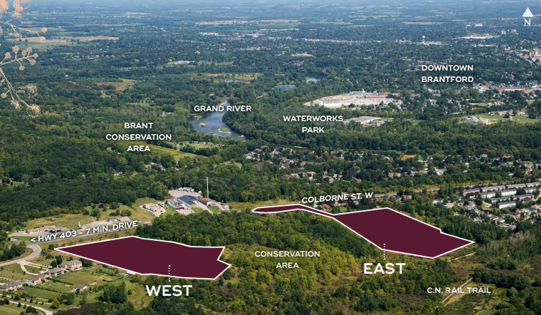 Aerial view of a landscape featuring two marked areas labeled "West" and "East" near Colborne St. W., with Sienna Woods adding natural charm. The Brant Conservation Area lies nearby, with roads, trees, and the Grand River visible. Downtown Brantford and neighboring towns can be seen in the distance.