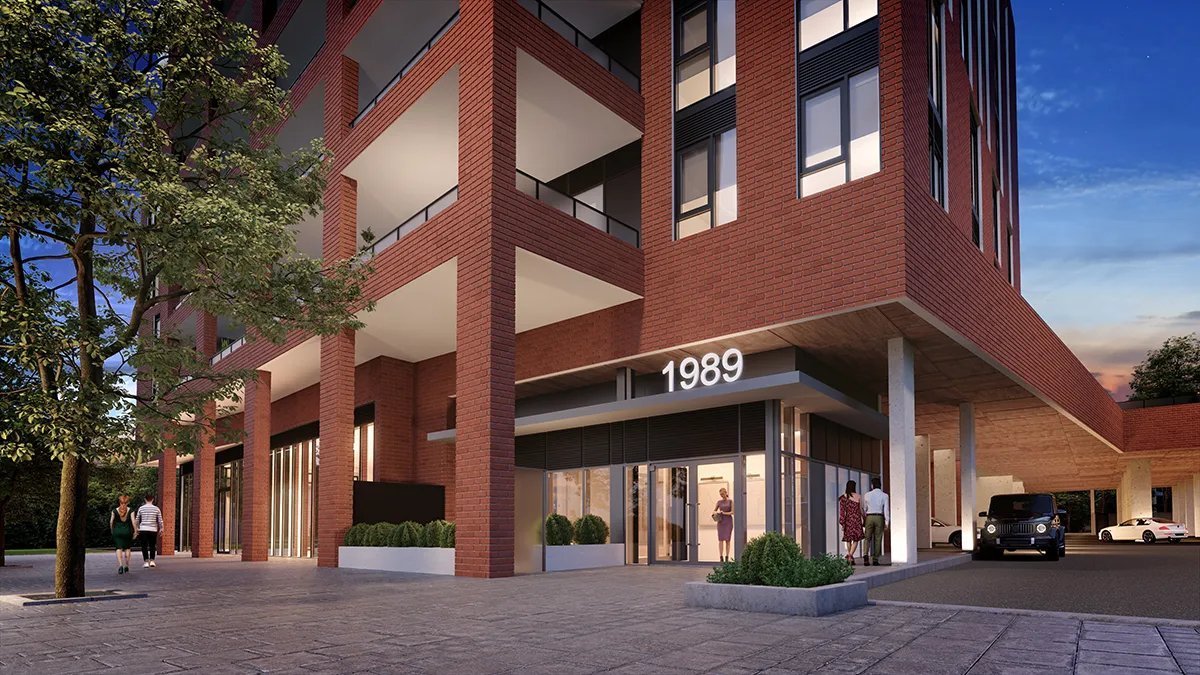 A modern multi-story brick condominium with large glass windows and balconies is illuminated at dusk. The entrance, with the number "1989" prominently displayed, features people walking and a parked black vehicle nearby. A tree is visible on the left.