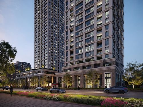 A cityscape at dusk showcases modern high-rise buildings with illuminated windows. Cars and people bustle below, flanked by trees along the street. The soft blue-gray sky adds to the urban ambiance, hinting at the promise of new homes rising in the dynamic GTA skyline.