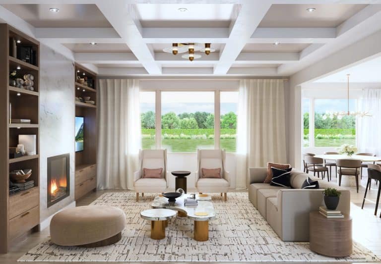 A modern living room in the Clarehaven estates with a coffered ceiling, large windows, and a view of a lush green landscape. The room features a light-colored L-shaped sofa, two armchairs, a fireplace, built-in shelves, and a round ottoman. A dining area is visible through a wide doorway.