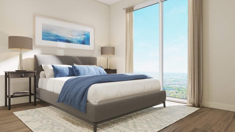 The modern bedroom in this new GTA home features a large bed with a gray headboard and chic white and blue bedding. Two nightstands and lamps flank the bed, while a large window with beige curtains frames views of the landscape. Framed artwork adorns the wall above.