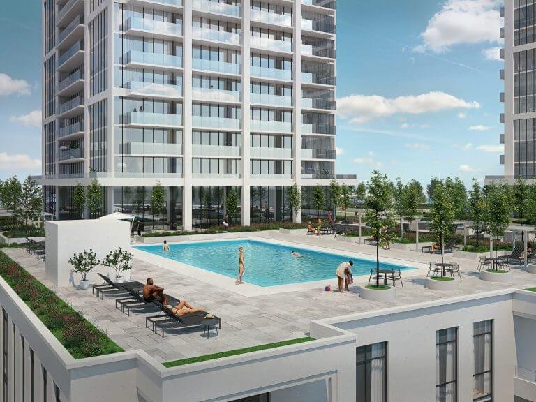 A modern residential complex, featuring new condos, boasts two tall buildings and a central outdoor swimming pool. Residents unwind on lounge chairs or stroll around the pool, enveloped by lush greenery. The sky is mostly clear with a few clouds.